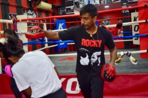 Coach Kumar demonstrating dodging techniques with a dedicated female boxer.