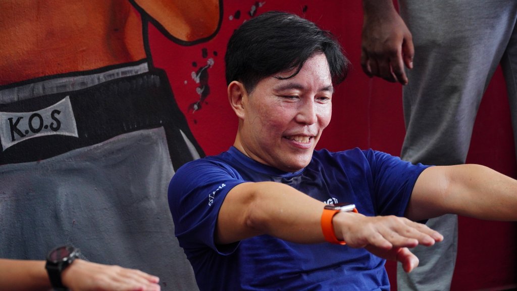 man smiling while performing sit ups at king of strength boxing gym.